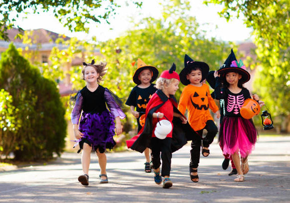 istockphoto-1173903234-612x612 Child in Halloween costume. Mixed race Asian and Caucasian kids trick or treat on suburban street. Little boy and girl with pumpkin lantern and candy bucket. Baby in witch hat. Autumn holiday fun.